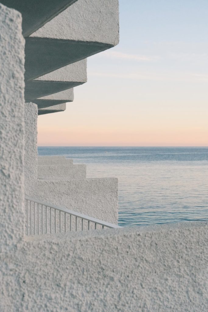 White textured building overlooking calm ocean at sunset